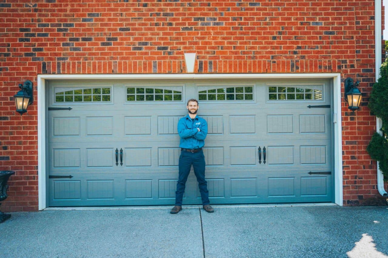 A Lee Company technician standing in front of a garage door after performing garage door repair