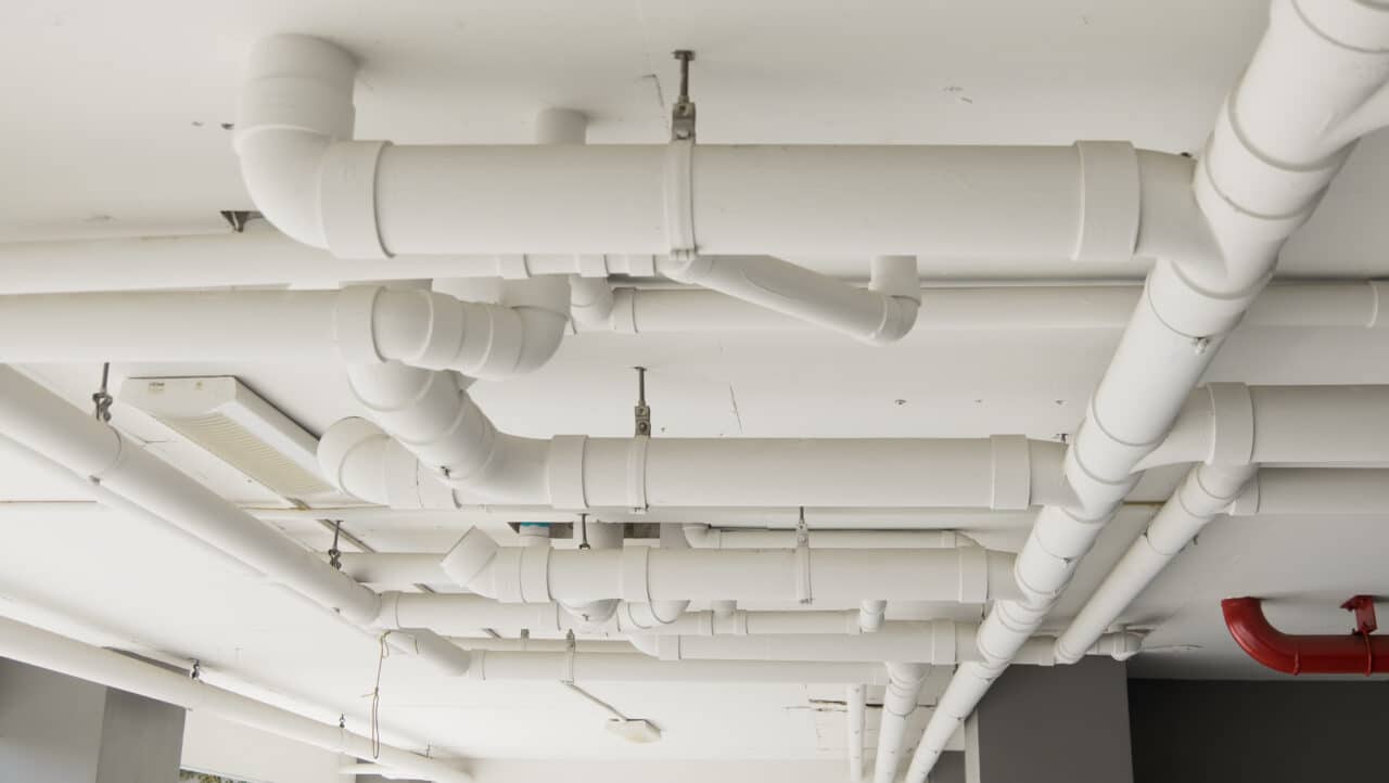 Drain pipes in a building representing drainage and plumbing maintenance.