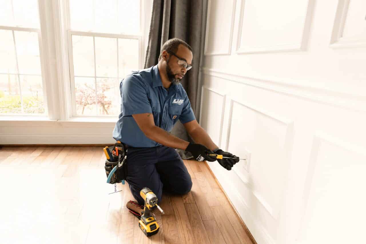 Lee Company technician performing routine electrical maintenance in a home